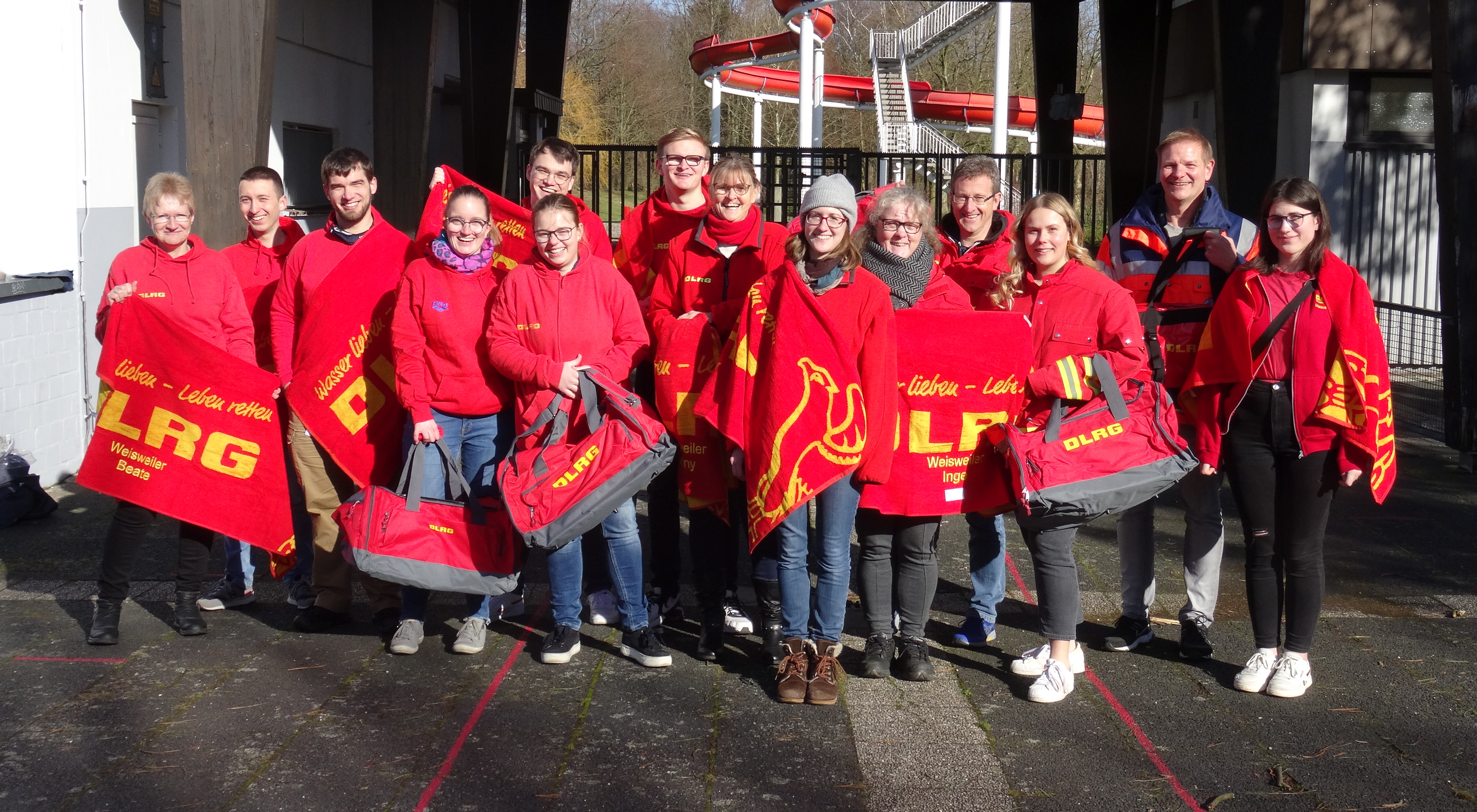 eine Gruppe Männer und Frauen in DLRG Kleidung vor dem Freibad Dürwiß